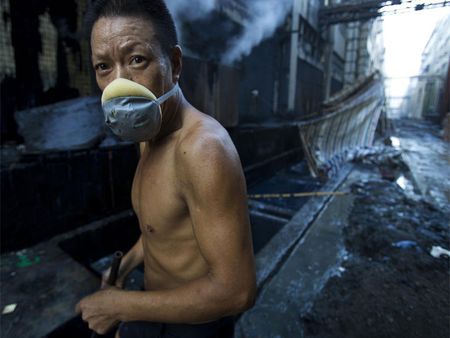 Ouvrier d'une usine de denim dans la ville de Xintang, surnommée la "Capitale mondiale du jean". En 2010, des niveaux anormalement élevés de métaux lourds hautement polluants ont été relevés dans le fleuve Dong adjacent, d'une couleur bleu-noir inquiétante. © Lu Guang / Greenpeace